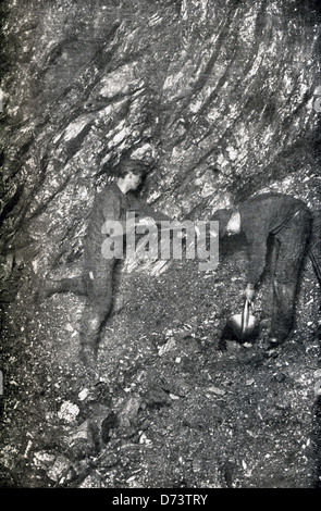 Two United States miners drill at the bottom of a coal mine in this photograph dating to the early 1900s. Stock Photo