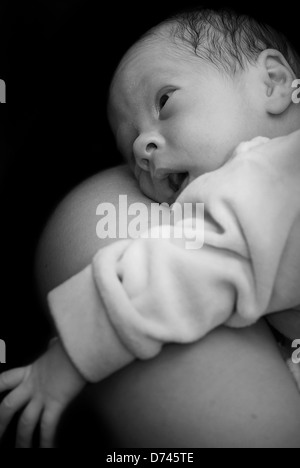 Newborn on mothers shoulder in black and white Stock Photo