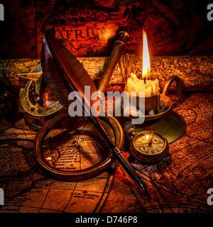 Vintage compass, magnifying glass, pocket watch, quill pen, spyglass lie on an old ancient map with a lit candle Stock Photo