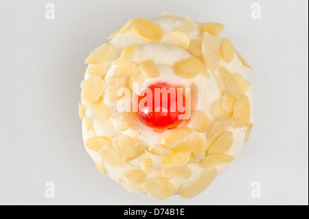 Flat lay view of cherry and flaked almond decorated cupcake on white background. Stock Photo