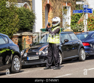 A traffic warden issues a ticket (PCN) for an illegally parked car Stock Photo