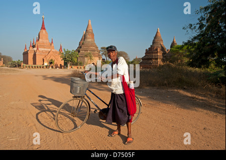 Burmese man and his bicycle standing in front of stone temples at sunset in Bagan Myanmar (Burma) Stock Photo