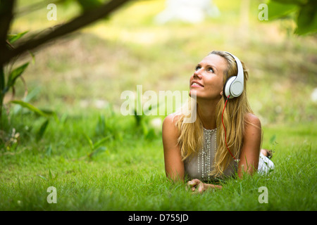 Lovely girl with headphones enjoying nature and music at sunny day. Stock Photo