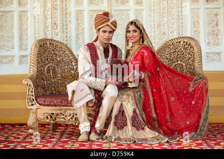 Indian bride and groom in traditional wedding dress sitting on a couch Stock Photo