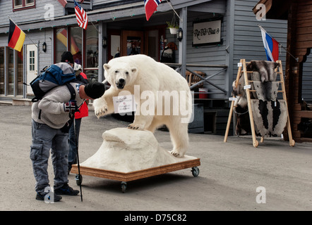 Tourist looking at 'Please Do Not Touch' sign on a stuffed polar bear in the shopping district of Longyearbyen, Svalbard Stock Photo