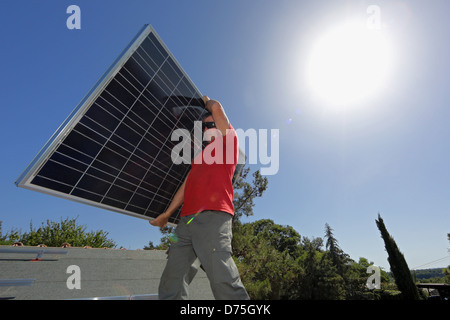 Torre Alfina, Italy, man carries a solar collector on the roof of a detached house Stock Photo