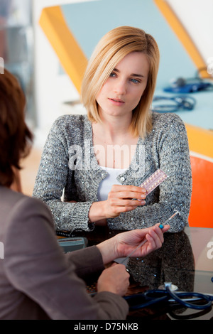 General practice doctor discussing oral contraception and intrauterine device with a young woman. Stock Photo
