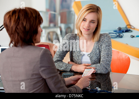General practice doctor discussing oral contraception with a young woman. Stock Photo