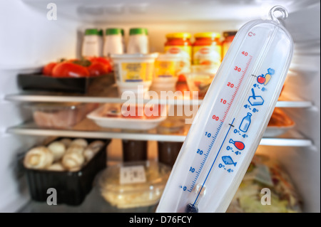 Thermometer in front of open fridge / refrigerator in kitchen Stock Photo