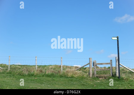 A wooden stile and fence in the countryside with a footpath sign. Stock Photo