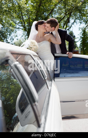 Newlywed Couple Standing Beside Limousine Stock Photo