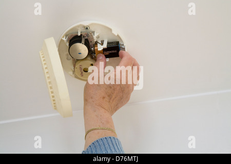 UK Elderly woman changing a battery in a smoke alarm Stock Photo