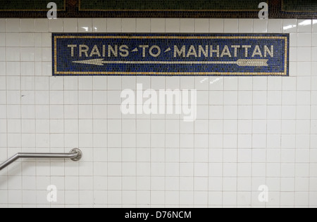 An old mosaic sign on the wall of a Brooklyn subway station that reads 'Trains To Manhattan' Stock Photo