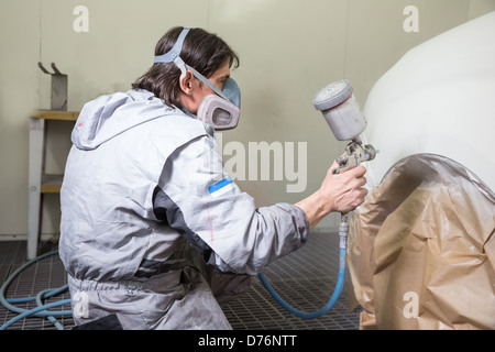 Car body painter spraying paint or color on bodywork in a garage or workshop with an airbrush Stock Photo