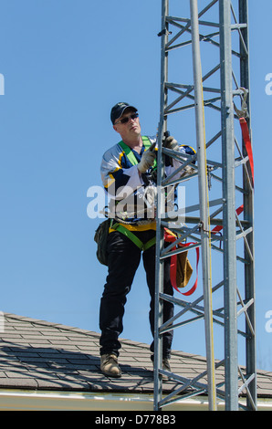 Man climbing antenna tower during amateur radio tower installation. Stock Photo