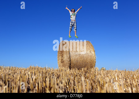 Torre Alfina, Italy, boy jumps on a straw bale in the air Stock Photo