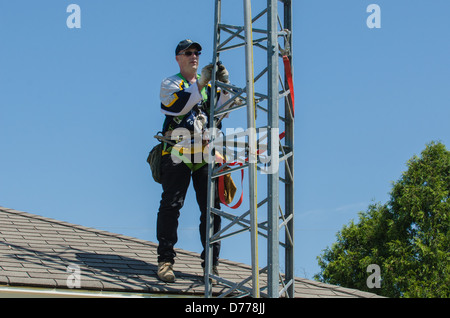 Man climbing antenna tower during amateur radio tower installation. Stock Photo