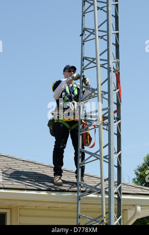 Man climbing antenna tower during amateur radio tower installation. Stock Photo