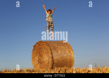 Torre Alfina, Italy, boy jumps on a straw bale in the air Stock Photo