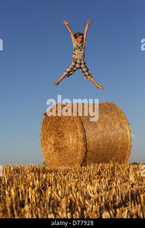 Torre Alfina, Italy, boy jumps on a straw bale in the air Stock Photo