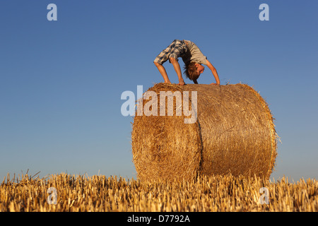 Torre Alfina, Italy, acrobatic boy bends on a straw bale Stock Photo