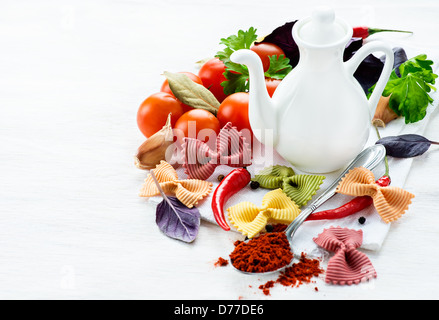 Uncooked multicolored pasta with tomatoes, fresh herbs and spices, selective focus Stock Photo