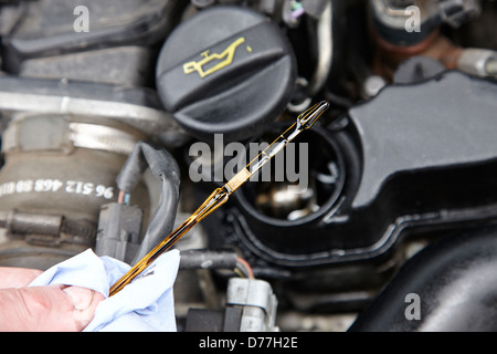 checking the oil level on the dipstick in a car engine compartment Stock Photo