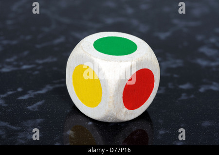 Standard six sided die with coloured spots against a black background. Stock Photo