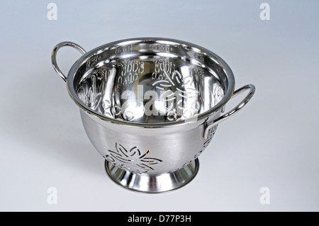 Modern stainless steel colander against a grey background. Stock Photo