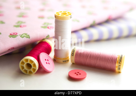 Sewing accessories - thread, fabric and buttons placed on a light grey background