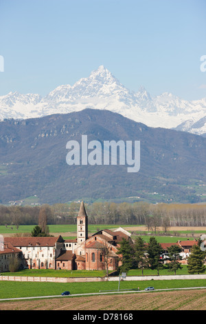 AERIAL VIEW. Staffarda Abbey in the Po Plain with Monte Viso in the distance. Near the town of Saluzzo, Province of Cuneo, Piedmont, Italy. Stock Photo