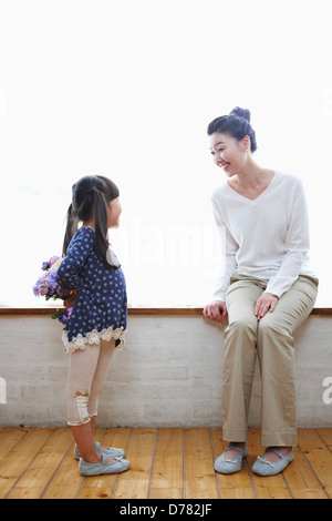 a girl hiding a bunch of flowers in front of mother Stock Photo