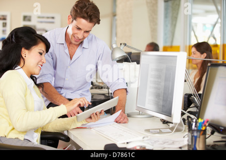 Workers Using Digital Tablet In Busy Creative Office Stock Photo
