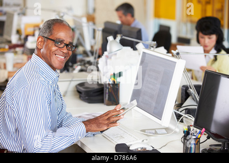 Man Using Digital Tablet In Busy Creative Office Stock Photo