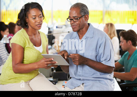 Workers Using Digital Tablet In Busy Creative Office Stock Photo