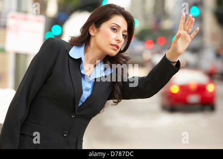 Businesswoman Hailing Taxi In Busy Street Stock Photo