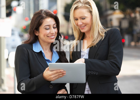 Two Businesswomen Using Digital Tablet Outside Office Stock Photo