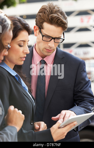 Businessman And Businesswomen Using Digital Tablet Outside Stock Photo