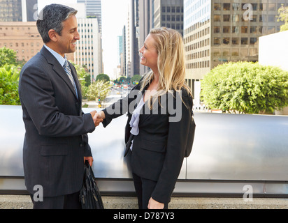 Businessman And Businesswoman Shaking Hands In Street Stock Photo