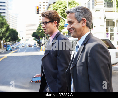 Two Businessman Chatting Whilst Crossing Street Stock Photo