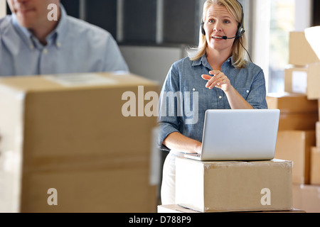 Female Manager Using Headset In Distribution Warehouse Stock Photo