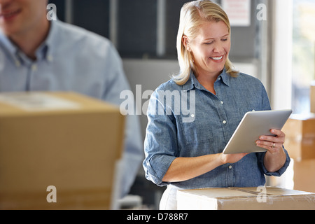 Manager Using Tablet Computer In Distribution Warehouse Stock Photo