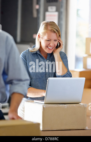 Female Manager Using Mobile Phone In Distribution Warehouse Stock Photo