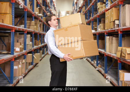 Man Carrying Boxes In Warehouse Stock Photo