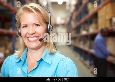 Businesswoman Using Headset In Distribution Warehouse Stock Photo
