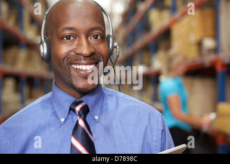 Businessman Using Headset In Distribution Warehouse Stock Photo