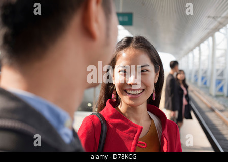 Young woman talking to man on railway platform, China Stock Photo