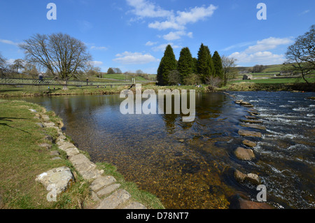 People Walking on the Suspension Bridge & Stepping Stones over the River  Wharfe near Hebden on the Dales Way Long Distance Footpath Yorkshire Stock Photo