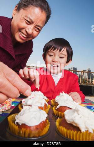 Grandmother and grandson decorating cupcakes Stock Photo