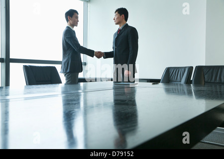 Businessmen shaking hands in meeting room Stock Photo